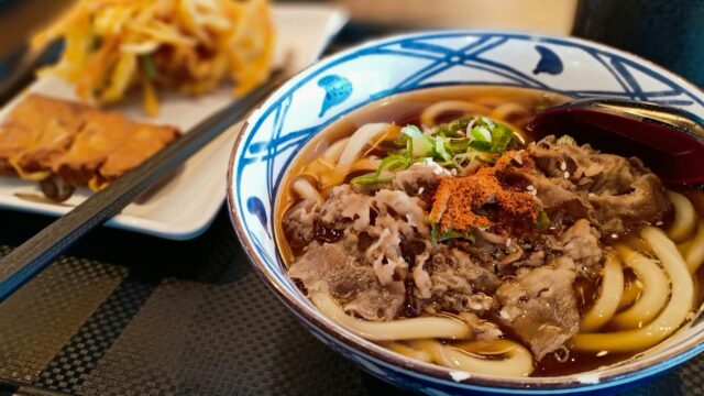 a blue and white bowl filled with noodles and meat